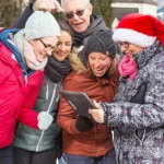 Eine Team in Winterkleidung löst Aufgaben auf einem iPad